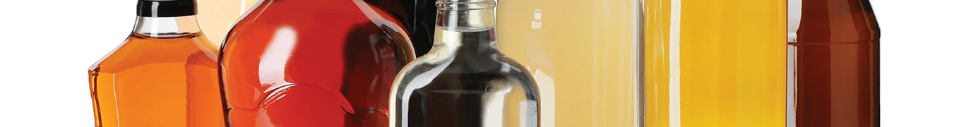 A collection of assorted glass bottles with different colored liquids on a white surface.