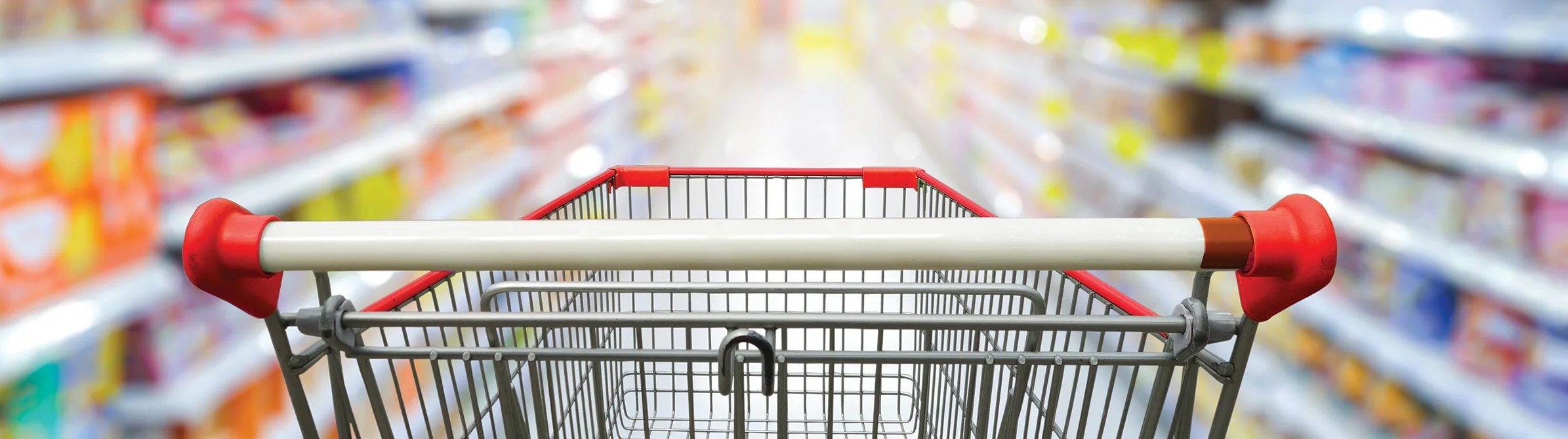 Shopping cart in the aisle of a supermarket with blurred shelves in the background.